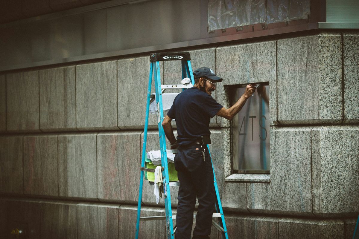 Reinigungsmitarbeiter bei professionellen Arbeiten auf einer Leiter
